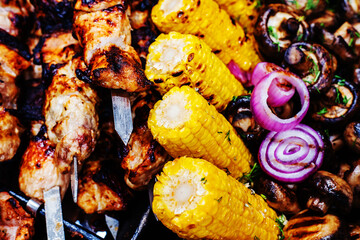 Grilled meat and corn. Barbecue and fruits fried on fire and coals. selective focus