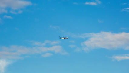 Naklejka na ściany i meble Airplane on a background of blue sky with clouds.