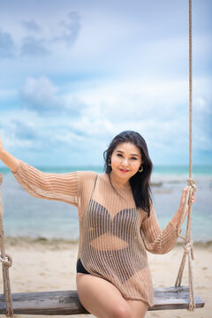 beautiful woman sitting on a swing on the beach on vacation