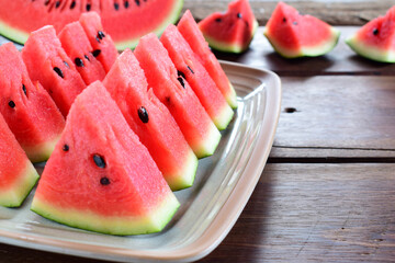 Sliced watermelon in ceramic dish on wooden table.