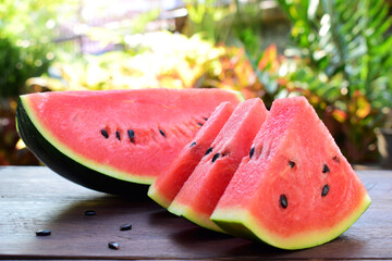 Sliced watermelon on wood table with warm colors in soft-focus in the background.