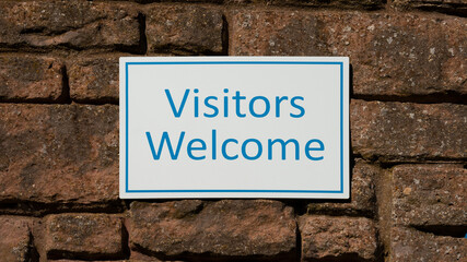 Visitors Welcome sign on brick background