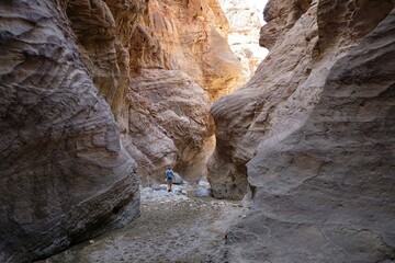 Dana Biosphere Reserve in Jordan. Amazing rocks in Wadi Ghuweir Canyon. Silhouette of hiking person on trail.	 - obrazy, fototapety, plakaty