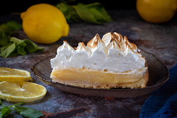 Lemon cake with protein cream, on a light background, with lemon slices and mint leaves.