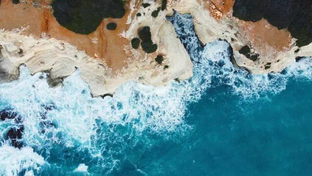 Pure blue ocean water waves with light reflections crush mountain at beautiful coastline, 4k slow motion