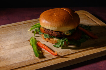 Fresh, delicious veggie falafel burger on a cutting board, on a red, rustic table.