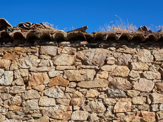 Close-up of a rustic stone wall with tiles and a black cable