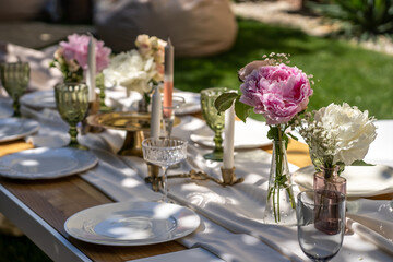 The table is set for special occasions. Empty plates and unusual glasses. vintage tray, candle holder and vases with beautiful flowers. Everything for a special day