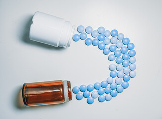 glass and White plastic pill's bottles with blue pills on white table. black background.  blue erection pills
