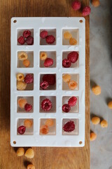 Freezing raspberries in water. Fruit ice. White silicone ice mold.