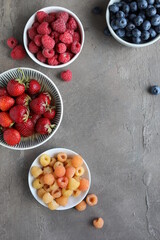 Many different ripe juicy berries in plates on the table. Summer flat lay. Raspberries, strawberries, cherries, cherries, blueberries.
