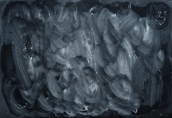 wet white chalk wipe marks on black foil background, dirty school board.