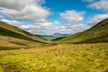 Obraz premium Beautiful mountainous landscape of the Trossachs National Park in Scotland in the summer with hills, valleys, river streams, reservoirs and mountain peaks