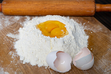 Making homemade dough for bread, pastry, and cookie. Wood rolling pin, flour, eggs. Rural food cooking. Top view
