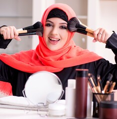 Beautiful woman in hijab applying make-up
