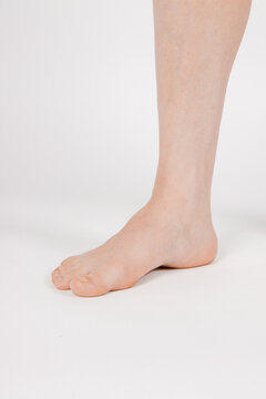 Barefoot and legs isolated on white background. Closeup shot of healthy beautiful female feet. Health and beauty concept. Side view of human foot ream with neutral manicure or pedicure. Sole of foot.