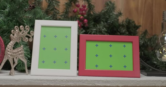 Christmas deer toy and photo frame mockups in front of christmas tree branches, slow motion