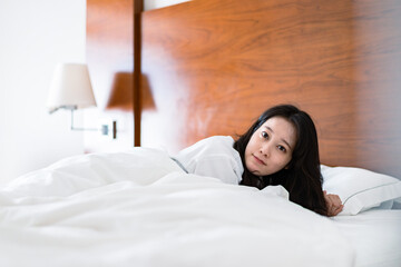 明るい時間にベッドで寝る若い女性
