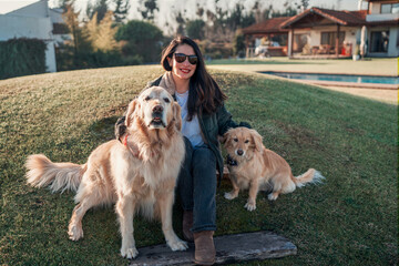 latin mature woman sitting outdoors smiling with her pets  at sunset portrait	