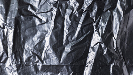 The background image of black plastic trash bags has creases creating a rough texture with light and shadow.