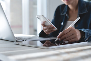 Close up of asian business woman using stylus pen on digital tablet, hand holding mobile phone...