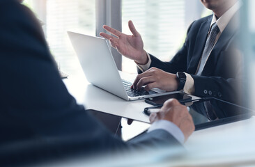 Two asian businessmen having a discussion during meeting and working on laptop computer in modern...