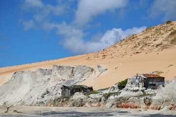 Poor house on the multicolored cliff. Hut used by fishermen for seasonal storage of boats and fishing gear. Cliffs of Morro Branco, Ceara state, Brazil