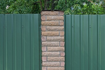 part of a private green metal and brown brick wall fence in the street