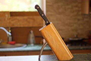 one black kitchen knife is placed in a brown wooden box on the table in the kitchen in the room