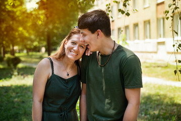 A happy woman with her almost adult son, a teenager, spend time together and laugh, recall funny situations from their lives, the focus is on mom. A real portrait of a mother and son
