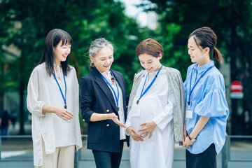 妊娠中の女性と話す、さまざまな年代の女性