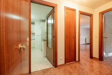 Hallway of a house with wooden doors, fitted wardrobes, reddish ges floors and access to other rooms