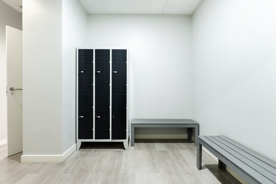 Locker room with black lockers and gray benches in the toilets of a gym