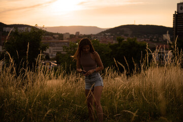 Young cheerful woman at sunset posing in the background of the city in the mountains.