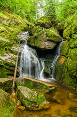 waterfall on mountain creek over big boulders long exposure