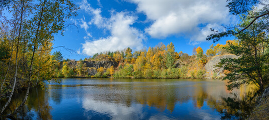 Fototapeta na wymiar flooded quarry surrounded by trees in autumn