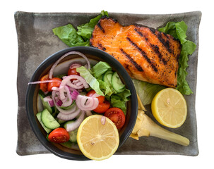 Salmon steak with a salad and lemon is isolated on white
