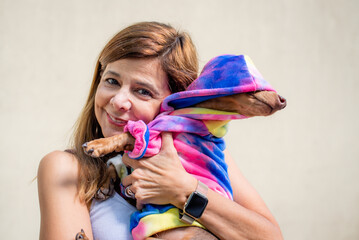 Latin woman holding her dog both dressed alike.  She is looking at camera.