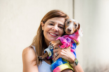 Latin woman holding her dog. Both are dressed alike and looking at camera.