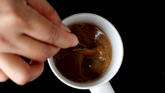 Top view Slow motion video image of a woman's hand brewing hot coffee in a white mug on black background-4k