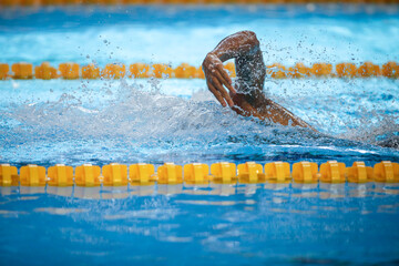 Details with a professional male athlete swimming in an olympic swimming pool freestyle.