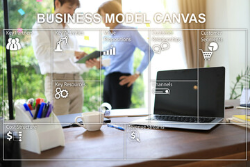 Business model canvas on the blurring work desktop background and two-person discussion beside the...