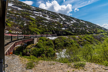 Fototapeta na wymiar A view down a train crossing a bridge over a ravine on the White Pass and Yukon railway near Skagway, Alaska in summertime