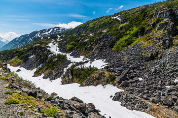 A view over a snow filled ravine from a train on the White Pass and Yukon railway near Skagway, Alaska in summertime