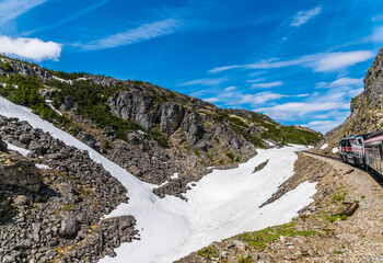 A view up a snow filled ravine from a train on the White Pass and Yukon railway near Skagway, Alaska in summertime