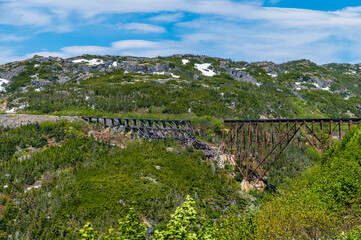 A view of a wrecked bridge from a train on the White Pass and Yukon railway near Skagway, Alaska in summertime