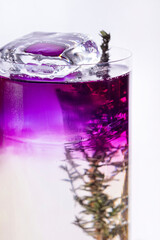 Cocktail with ice, purple syrup and thyme