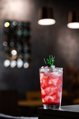 A cocktail with syrup, ice and rosemary