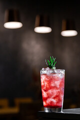 A cocktail with syrup, ice and rosemary
