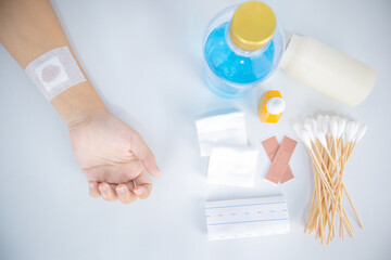 Injured arm and first aid kit on white background.